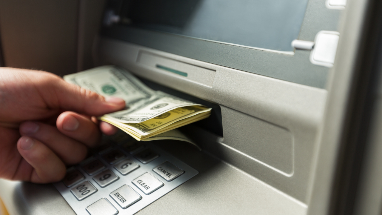 Person withdrawing cash from ATM with crypto card